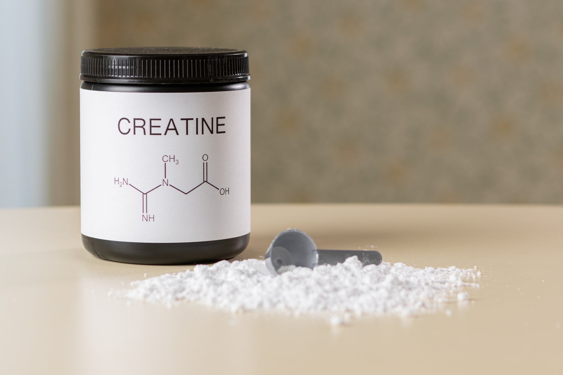 Kreatin Monohydrat - boks det står creatine på med pulver foran på et bord